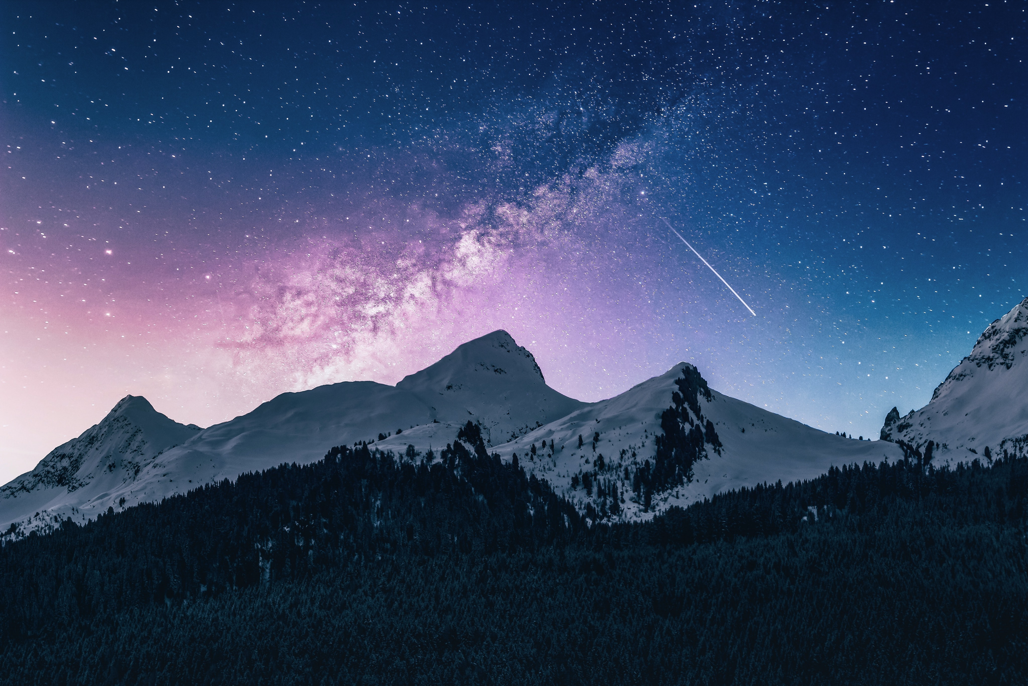 A white mountain stands tall behind a forest and under a purple and blue night sky, littered with stars. A comet streaks across the scene in the background.